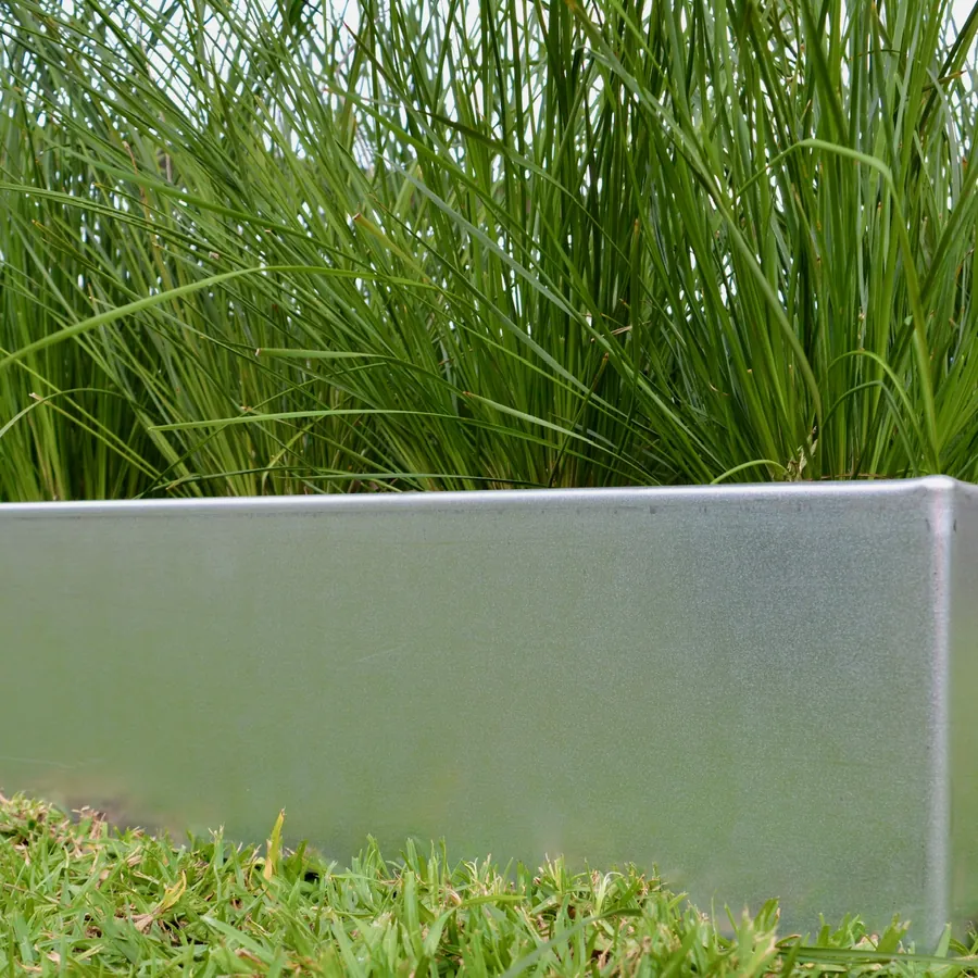 Silver-grey steel edging along a planted border beside a lawn