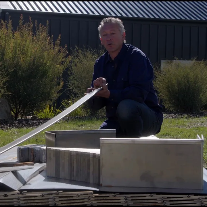 A still from the FormBoss installation video: steel edging strips and fittings laid out on a lawn